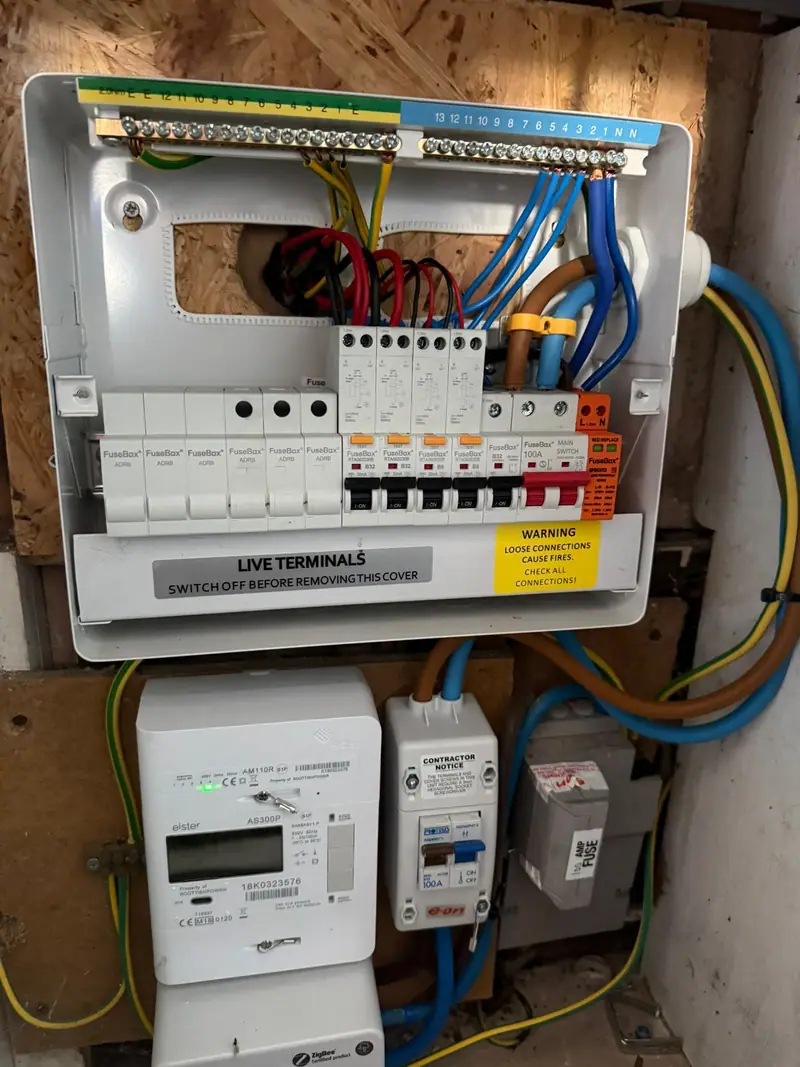 A new consumer unit above the meter with surge protection, the kind of board we fit in Bury