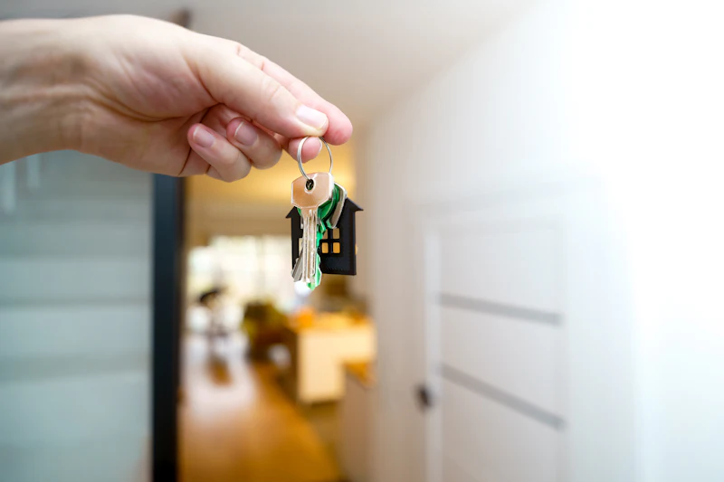 A hand holding a set of house keys in a hallway