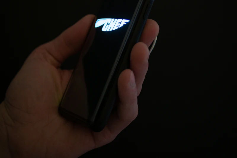 A hand holding a phone with its torch on in a dark room