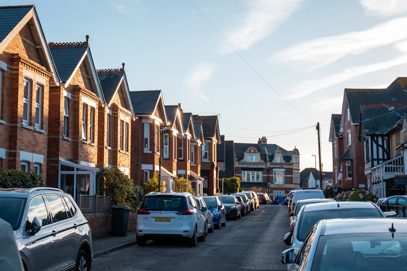 Red-brick terraced houses with cars parked along a British residential street