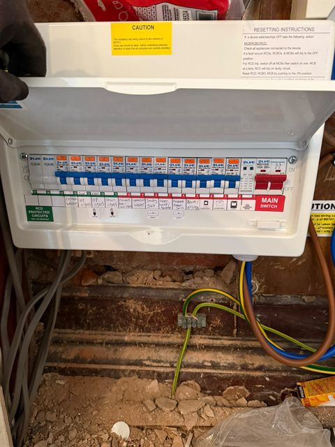 A finished consumer unit with the lid open, an RCBO on every circuit, surge protection fitted and every way written up on the schedule.