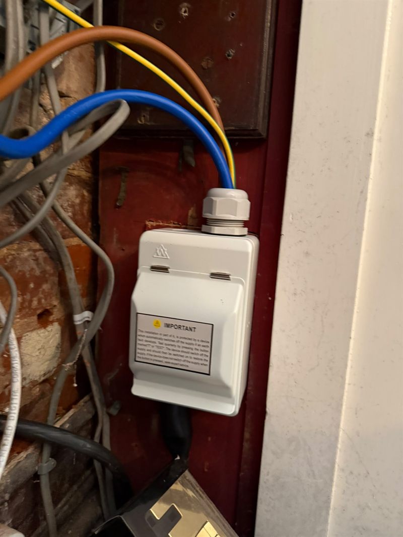 A separate weatherproof RCD enclosure fitted nearby, glanded and labelled with its own test notice.